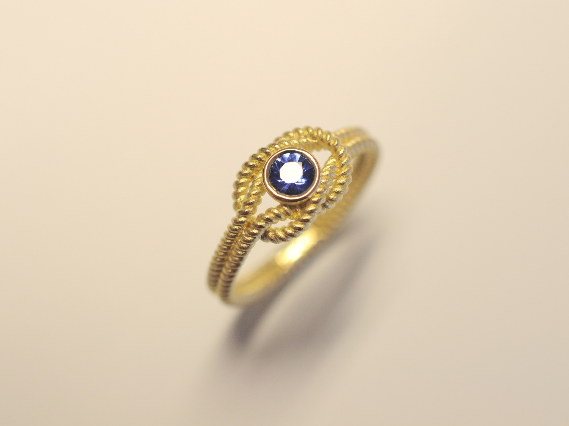 Goldring Kreuzknoten aus 750 Gelbgold mit tiefblauem 0,27 ct Saphir im Brillantschliff
