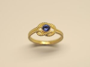 Goldring Kreuzknoten aus 750 Gelbgold mit tiefblauem 0,27 ct Saphir im Brillantschliff