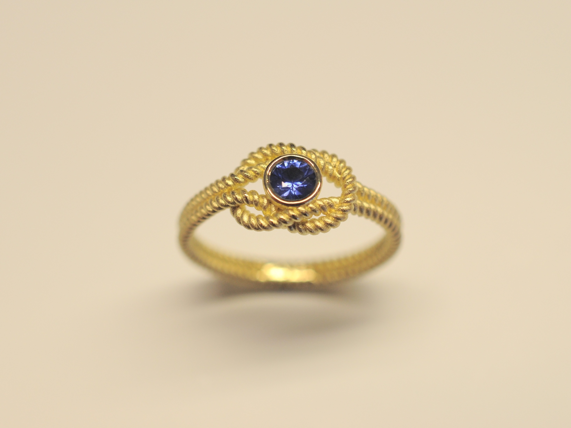 Goldring Kreuzknoten aus 750 Gelbgold mit tiefblauem 0,27 ct Saphir im Brillantschliff