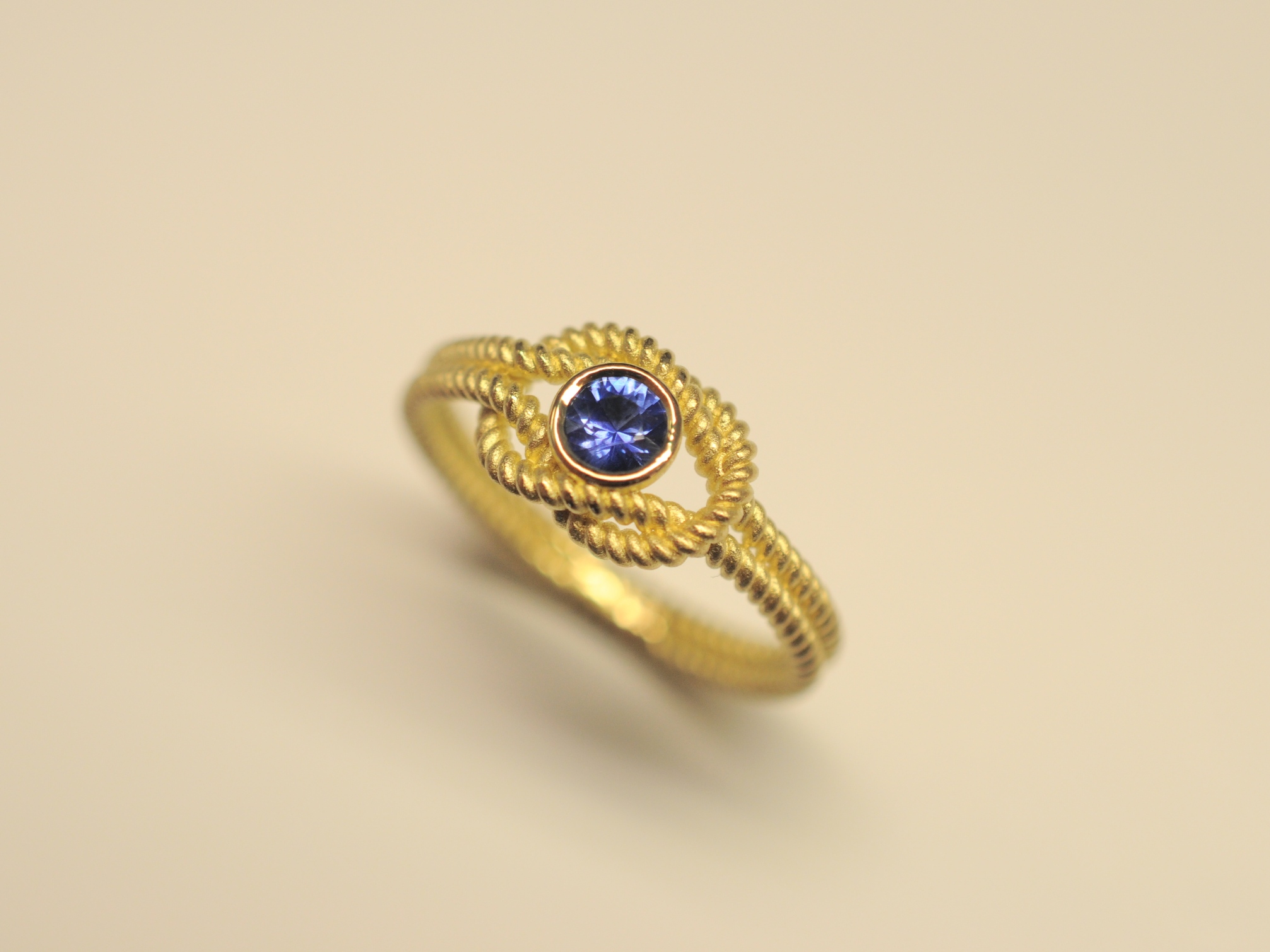 Goldring Kreuzknoten aus 750 Gelbgold mit tiefblauem 0,27 ct Saphir im Brillantschliff
