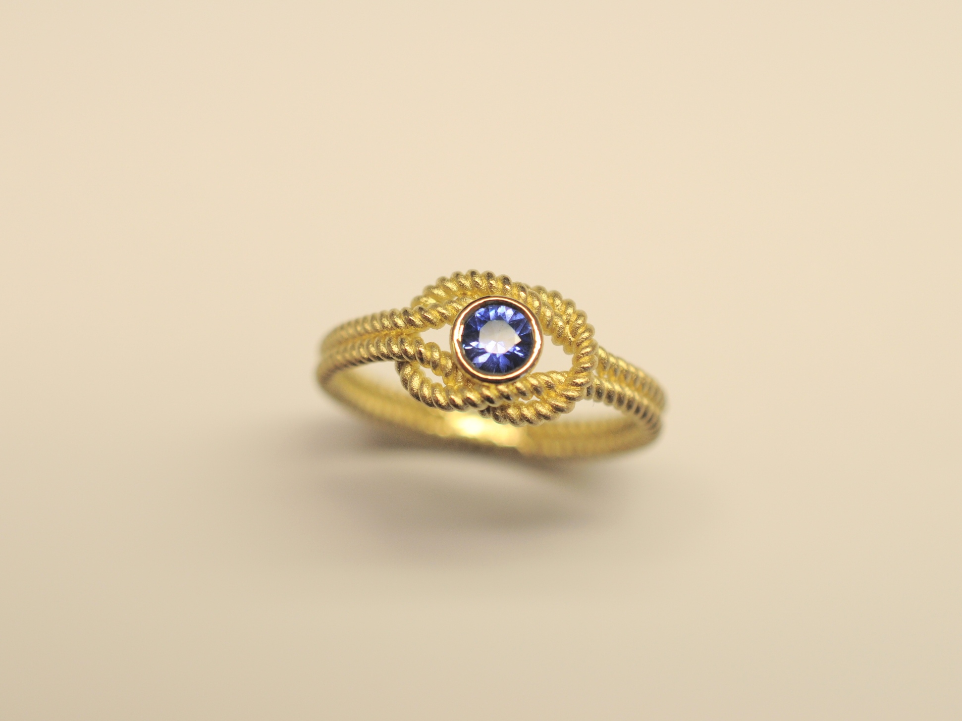 Goldring Kreuzknoten aus 750 Gelbgold mit tiefblauem 0,27 ct Saphir im Brillantschliff